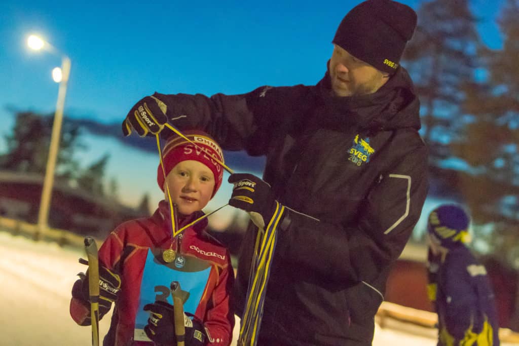 Albin Fundin från Sveg får en välförtjänt medalj av Janne Westfält efter målgång i Barnens Vasalopp 2018. Foto: Morgan Grip
