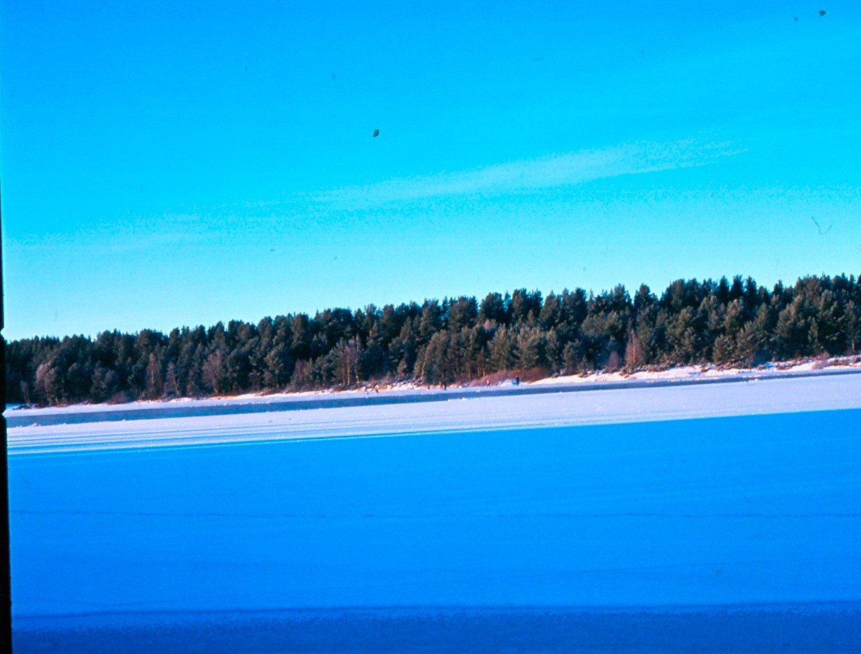 Långt framskriden islossning på Ljusnan. I bakgrunden nära stranden pimpelfiskare som försöker sig på de alla sista nappen under en värmande sol och blå himmel. Foto: Gustaf Persson